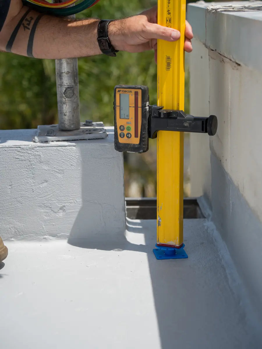 Tile installer using spirit level to set height on Screedex® screed system at floor perimeter